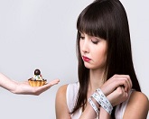 אישה מנסה לעמוד בפיתוי של אכילת עוגה